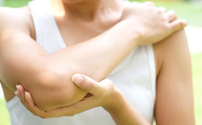 A woman holding her elbow in pain